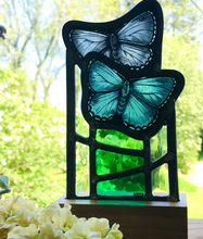 Load image into Gallery viewer, Stained glass standing panel of two blue butterflies flying above green glass in various hues
